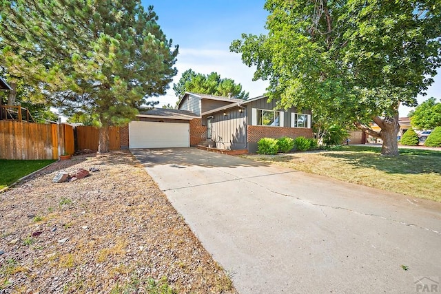 130 Montcalm Dr, Pueblo, CO 81005 - mid-century modern home featuring board and batten siding, brick siding, an attached garage, and driveway