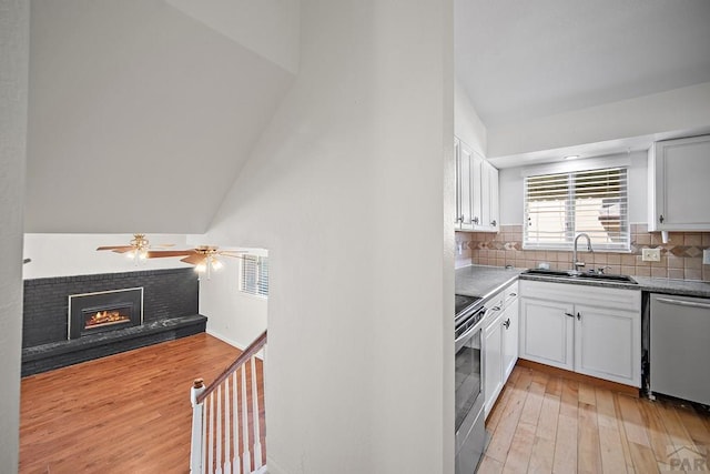 130 Montcalm Dr, Pueblo, CO 81005 - kitchen with appliances with stainless steel finishes, light wood finished floors, a ceiling fan, white cabinetry, and a fireplace