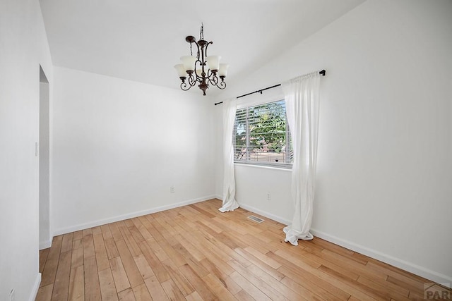 130 Montcalm Dr, Pueblo, CO 81005 - spare room featuring a chandelier, wood finished floors, and vaulted ceiling