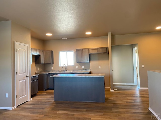 kitchen featuring a kitchen island, light countertops, a sink, and wood finished floors