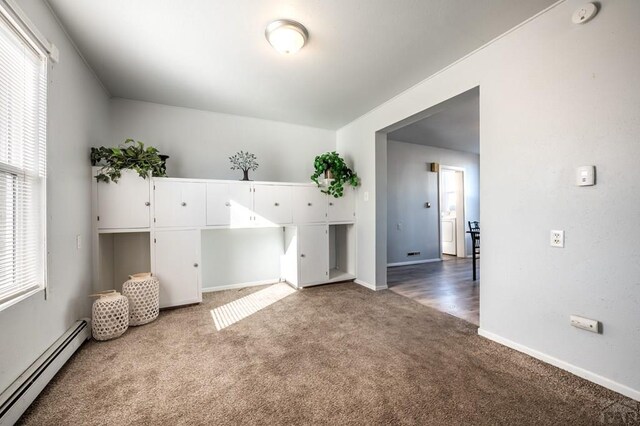 spare room with dark colored carpet, baseboards, and baseboard heating