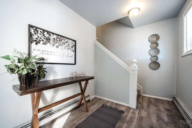 stairway featuring baseboards, baseboard heating, and wood finished floors