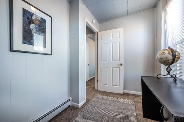 interior space featuring dark colored carpet, baseboard heating, and baseboards