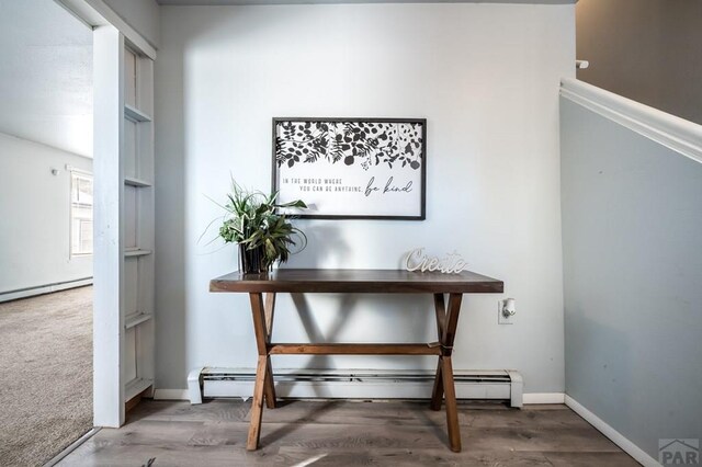 interior space featuring baseboards, baseboard heating, and wood finished floors