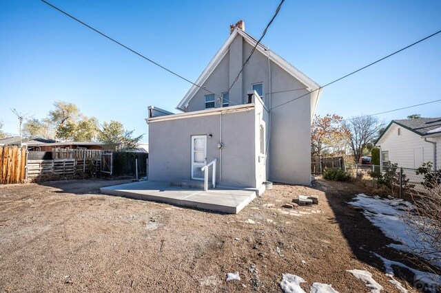 rear view of house with a patio area, fence, and stucco siding