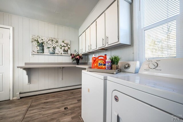 laundry area featuring a baseboard radiator, cabinet space, dark wood finished floors, and separate washer and dryer