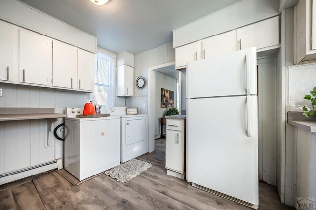 kitchen featuring light countertops, washer and dryer, freestanding refrigerator, and white cabinets