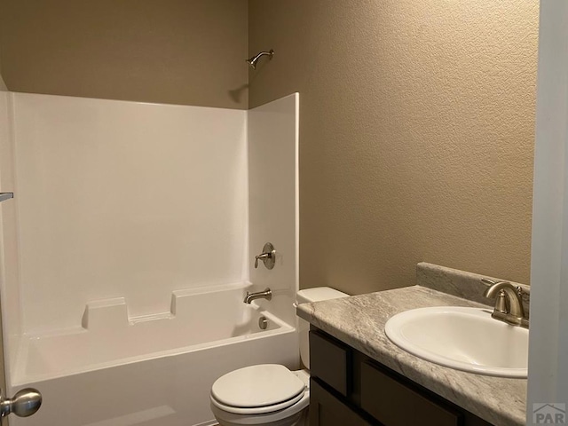 bathroom with vanity, shower / tub combination, toilet, and a textured wall