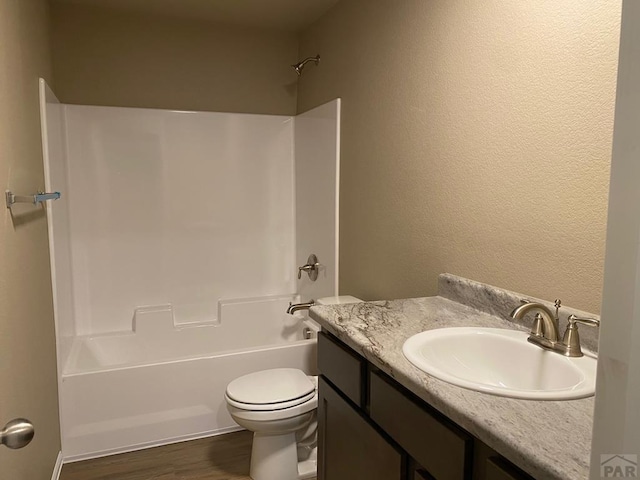 bathroom featuring vanity, toilet, shower / bathing tub combination, and wood finished floors