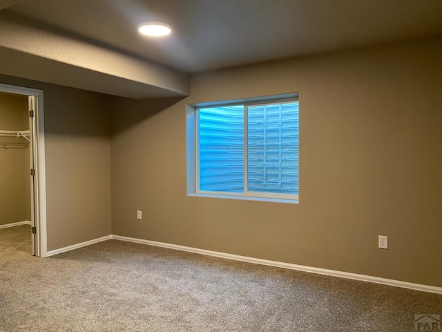 unfurnished bedroom with a walk in closet, carpet floors, baseboards, and a closet