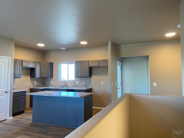 kitchen featuring recessed lighting, gray cabinets, dark wood-style flooring, light countertops, and a center island