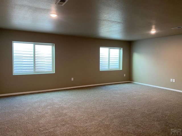 spare room with visible vents, baseboards, carpet, and a textured ceiling