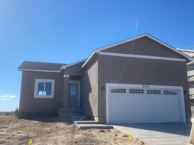 view of front of house featuring stucco siding, concrete driveway, and an attached garage