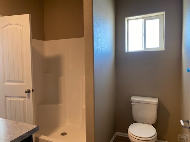 full bathroom featuring vanity, toilet, a walk in shower, and baseboards