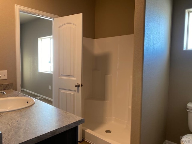 bathroom with vanity, a shower stall, and toilet