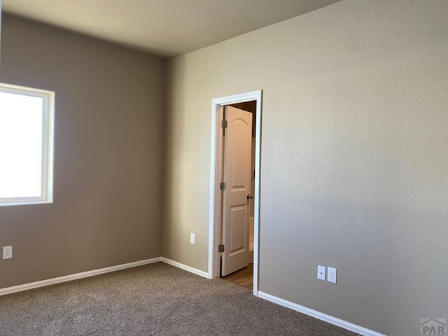 empty room with baseboards and dark carpet