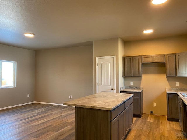 kitchen with light countertops, wood finished floors, baseboards, and a center island