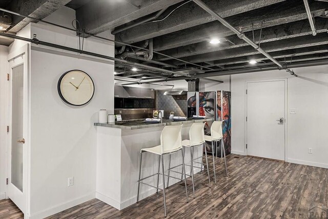 kitchen featuring tasteful backsplash, dark countertops, baseboards, and wood finished floors