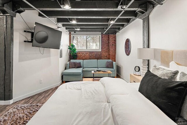 living area featuring baseboards, brick wall, and wood finished floors