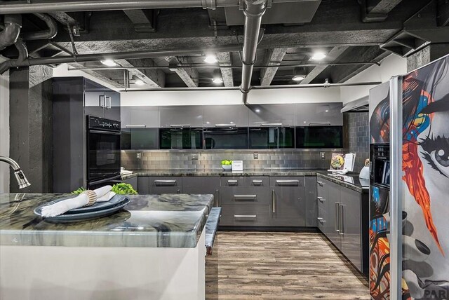 kitchen with gray cabinets, stainless steel countertops, decorative backsplash, wood finished floors, and stainless steel fridge with ice dispenser