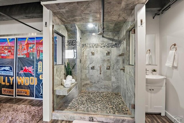 full bath featuring a sink, a shower stall, baseboards, and wood finished floors