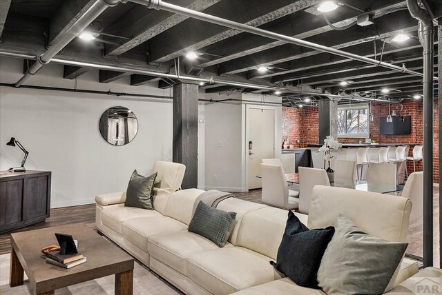 living room with brick wall, baseboards, and wood finished floors