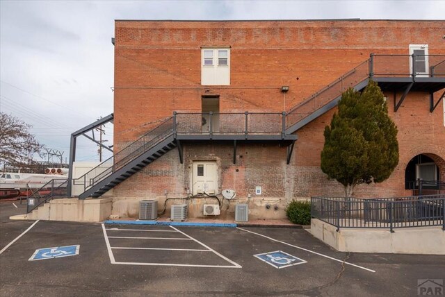 view of property featuring uncovered parking, stairway, and central air condition unit