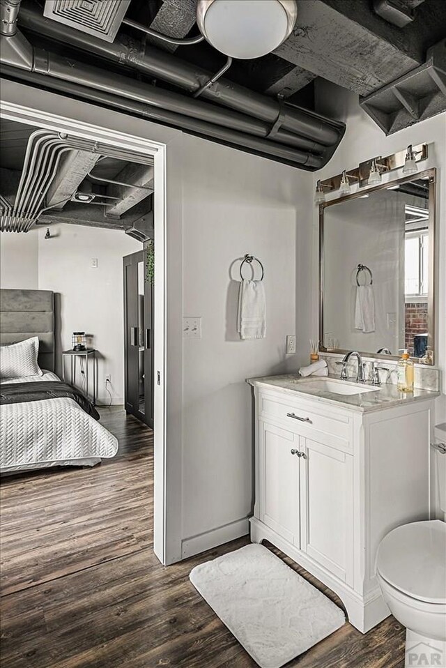 bathroom featuring toilet, visible vents, wood finished floors, and vanity