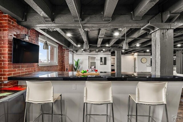 kitchen featuring dark countertops, brick wall, and a breakfast bar area