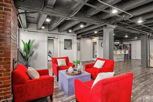 basement with brick wall, baseboards, and dark wood-style flooring