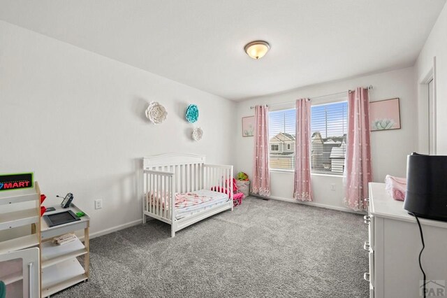 carpeted bedroom with a crib and baseboards