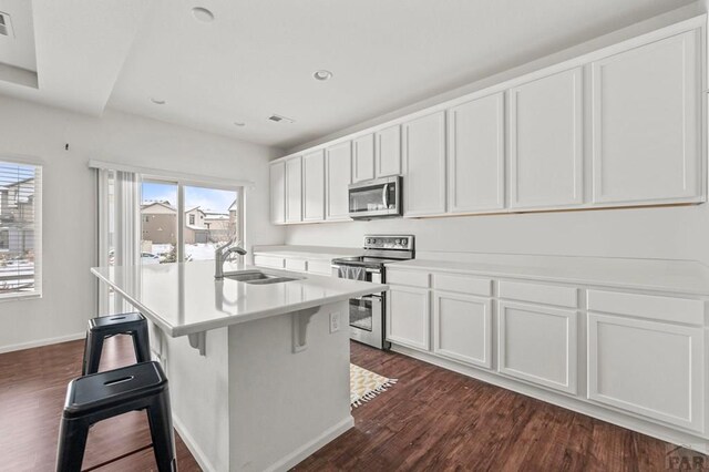 kitchen with a center island with sink, white cabinets, appliances with stainless steel finishes, light countertops, and a sink