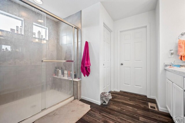 bathroom featuring visible vents, a shower stall, vanity, wood finished floors, and baseboards