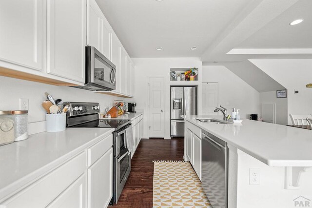 kitchen featuring a sink, white cabinets, light countertops, appliances with stainless steel finishes, and a center island with sink