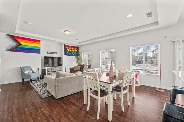 dining space with baseboards, visible vents, a raised ceiling, and dark wood-type flooring