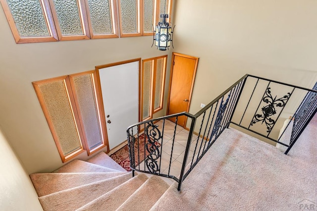 stairway featuring carpet flooring and a towering ceiling