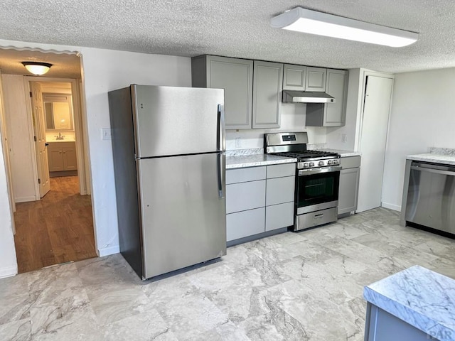 kitchen featuring stainless steel appliances, under cabinet range hood, and gray cabinetry