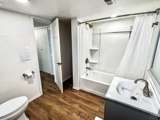 full bathroom with a textured ceiling, toilet, wood finished floors, vanity, and shower / bath combo with shower curtain