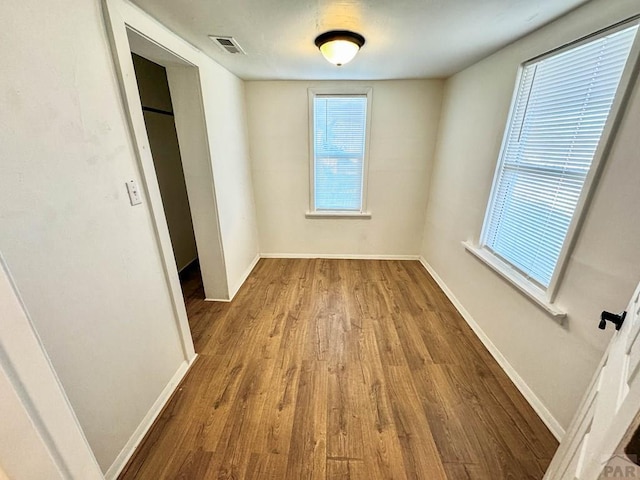 unfurnished bedroom featuring visible vents, baseboards, and wood finished floors