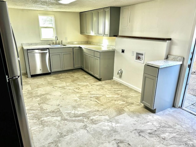 kitchen featuring gray cabinets, light countertops, appliances with stainless steel finishes, a sink, and a textured ceiling