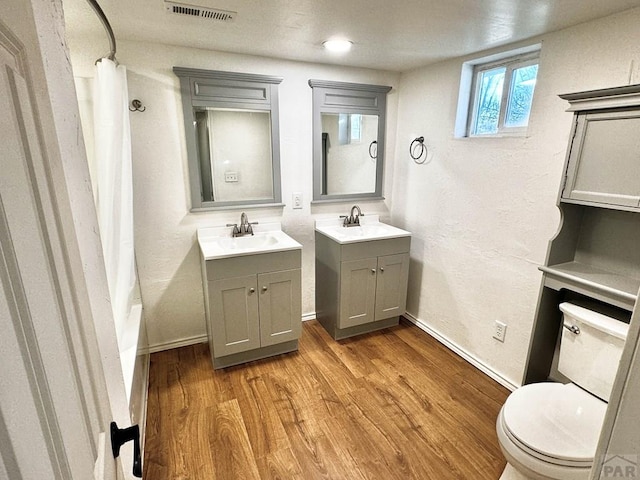 bathroom featuring two vanities, visible vents, a sink, and wood finished floors