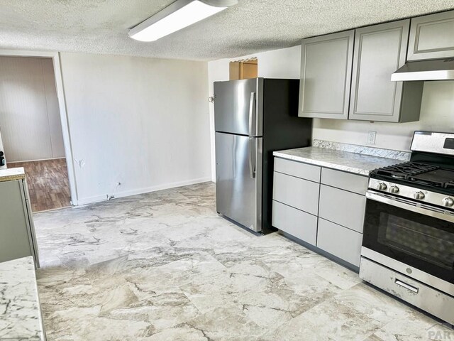 kitchen featuring stainless steel appliances, gray cabinets, light countertops, a textured ceiling, and under cabinet range hood