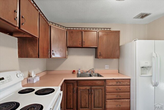 kitchen with white appliances, a sink, visible vents, light countertops, and brown cabinets