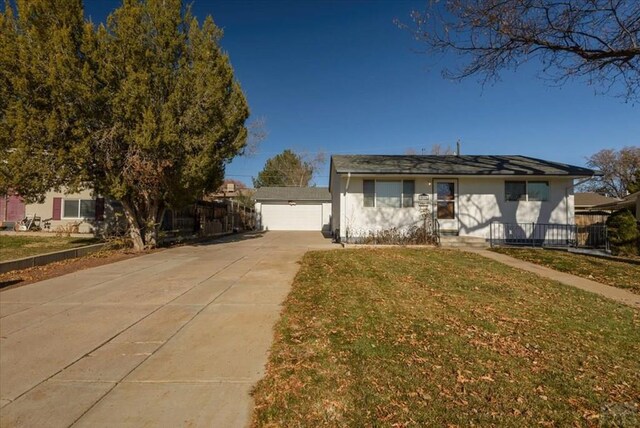 view of front facade featuring driveway, stucco siding, an outdoor structure, and a front yard