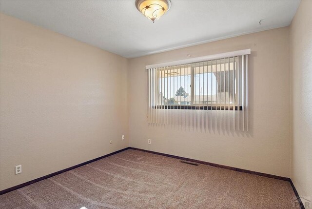 carpeted spare room with baseboards