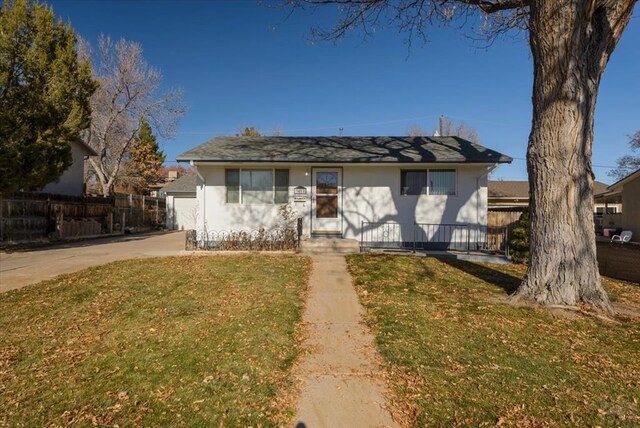 view of front of house with concrete driveway, a front yard, and fence