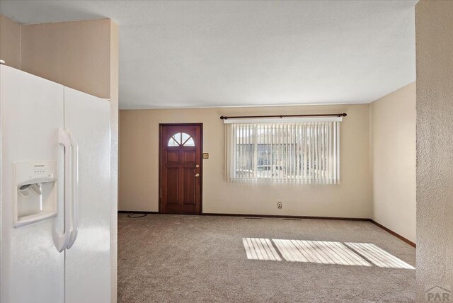 entryway featuring light carpet and baseboards