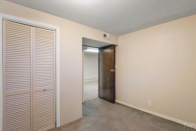 unfurnished bedroom featuring light colored carpet, a closet, visible vents, and baseboards