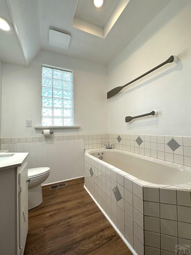 bathroom with visible vents, toilet, a wainscoted wall, wood finished floors, and vanity