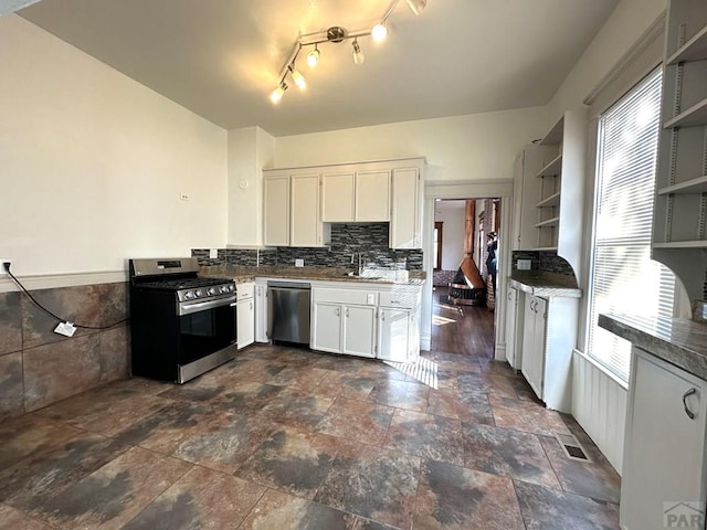 kitchen featuring white cabinets, a wainscoted wall, appliances with stainless steel finishes, stone finish flooring, and open shelves